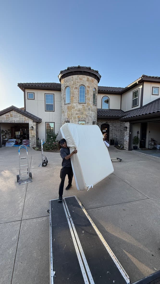 A Full Motion Services crew member carefully carrying a mattress out of a Fort Worth home